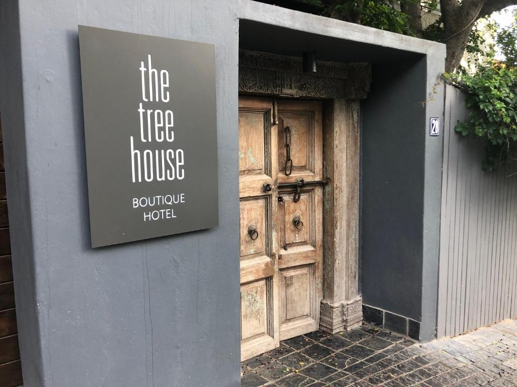 una señal en el lateral de un edificio con una puerta de madera en The Tree House Boutique Hotel by The Living Journey Collection, en Ciudad del Cabo