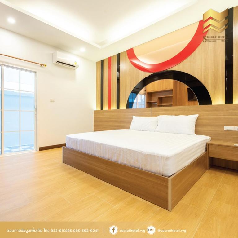 a bedroom with a bed and a painting on the wall at Secret Hotel in Rayong