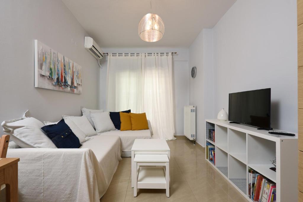 uma sala de estar com um sofá branco e uma televisão em #Luxlikehome - Rigas Apartment em Tessalônica