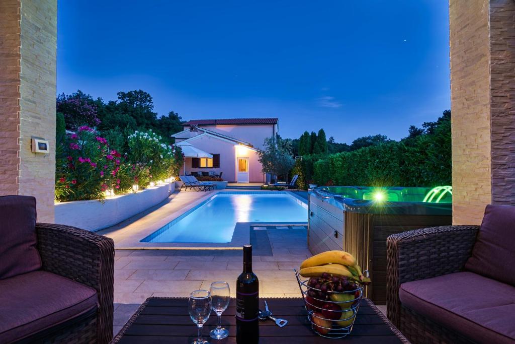 a bottle of wine on a table next to a swimming pool at Villa Ines in Labin