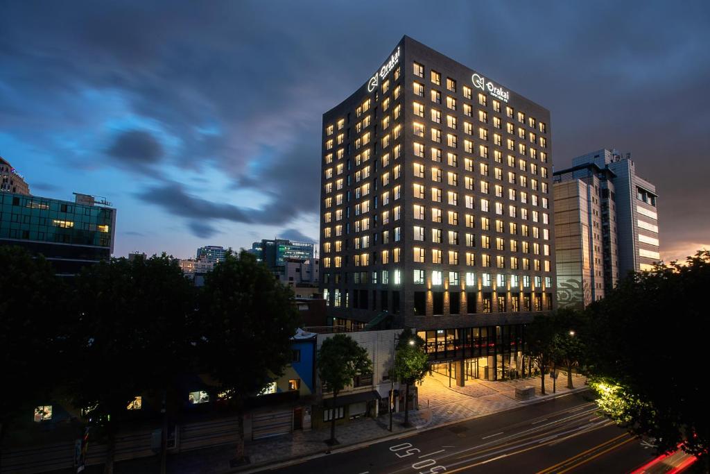 a tall building with lights on in a city at Orakai Daehakro Hotel in Seoul