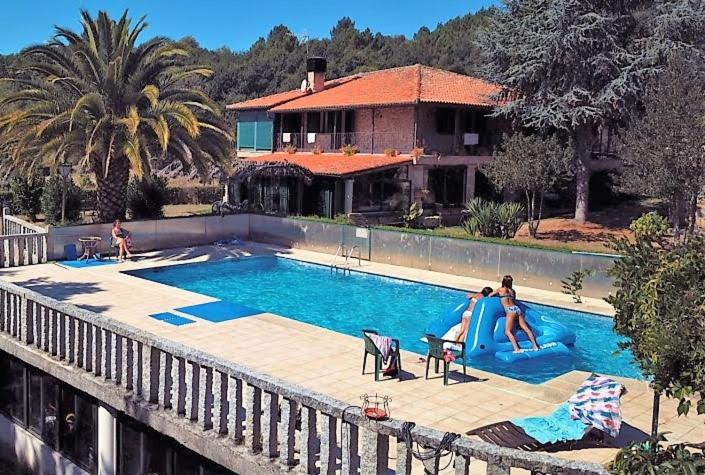 a swimming pool with two people on a slide in front of a house at Aldea Figueiredo in Ourense