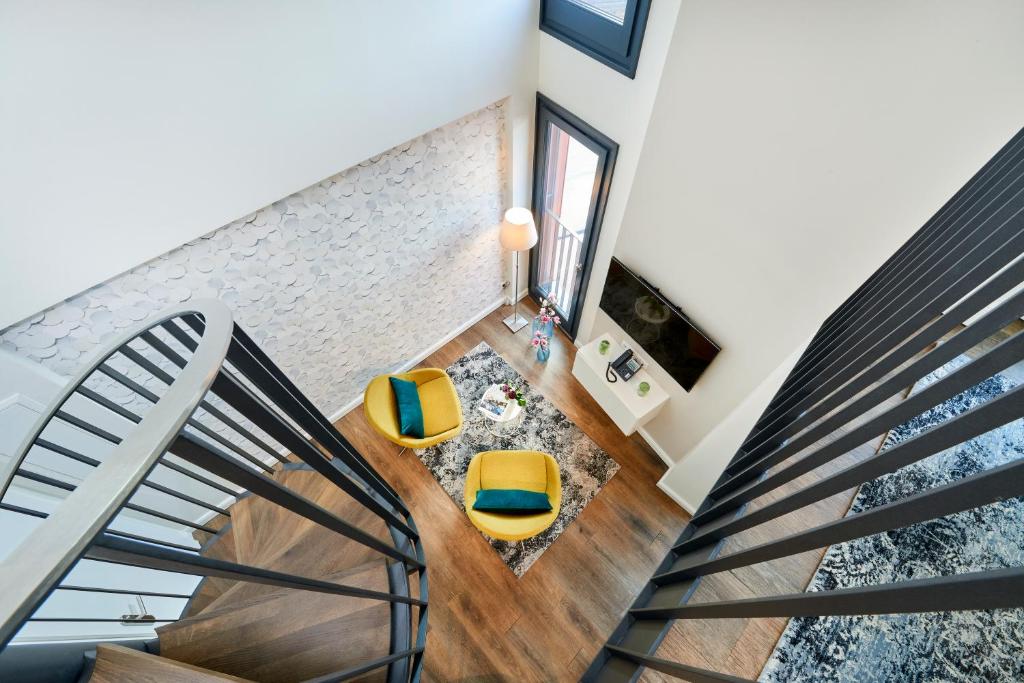 a staircase with yellow chairs in a living room at ÜberFluss Serviced-Apartments in Bremen