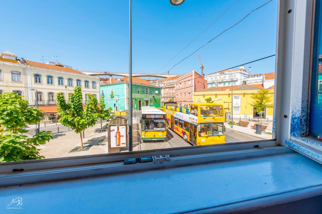 Twee dubbeldeksbussen staan voor een raam geparkeerd. bij SwissLisbon Guest House in Lissabon