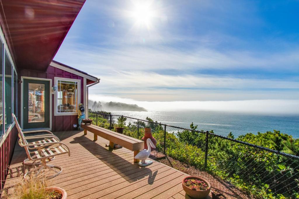 a house with a deck with a bench and the ocean at Whale Vista in Depoe Bay