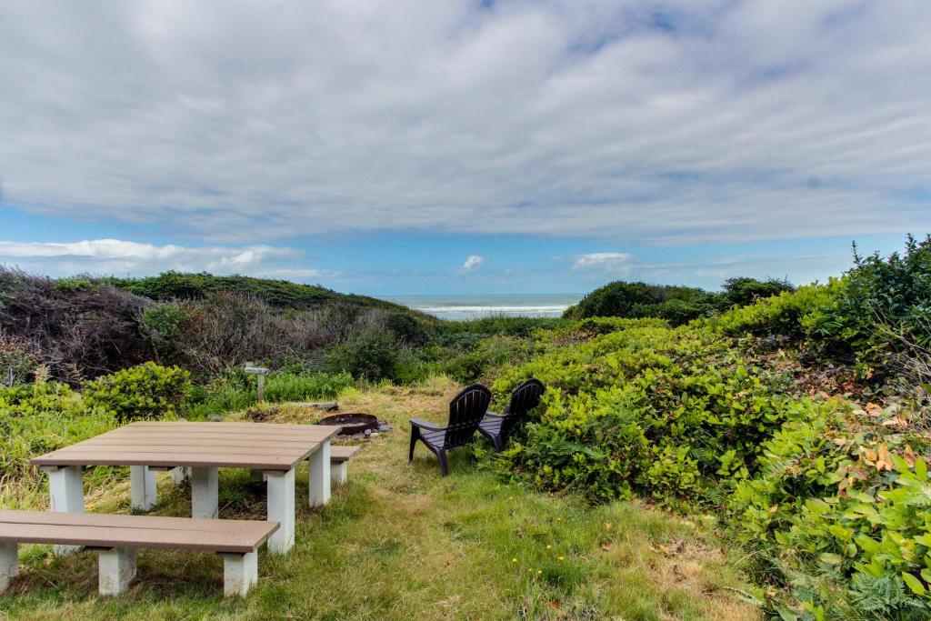 una mesa de picnic y dos sillas sentadas junto al océano en Dulcinea's Cabin, en Yachats