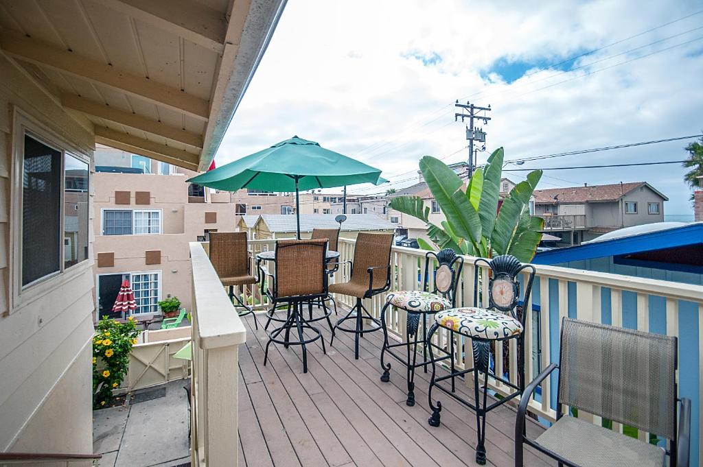 balcón con mesa, sillas y sombrilla en Mimi's and Nana's Beach House en San Diego