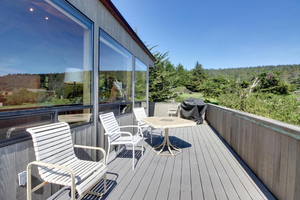 a deck with chairs and a table and windows at Audubon House in Sea Ranch