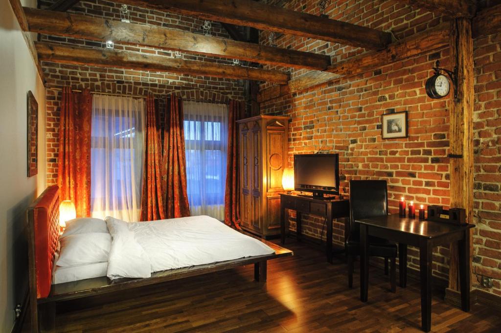 a bedroom with a bed and a desk and a brick wall at Apartamenty Chleb i Wino Toruń in Toruń