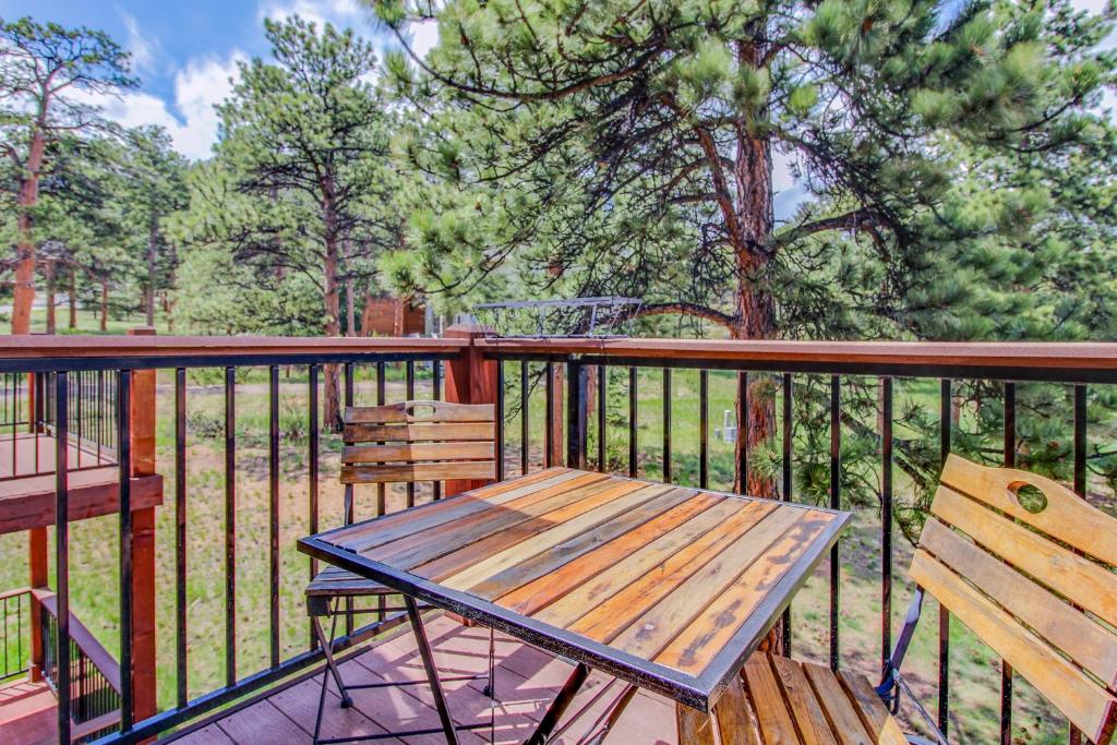a wooden table and chairs on a deck with trees at The Pine Cone - Permit #3255 in Estes Park