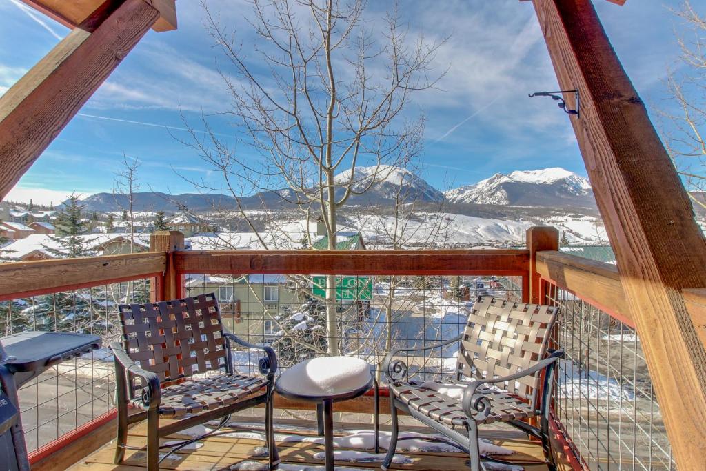 dwa krzesła i stół na balkonie z pokrytymi śniegiem górami w obiekcie Dillon Ridge Retreat w mieście Dillon