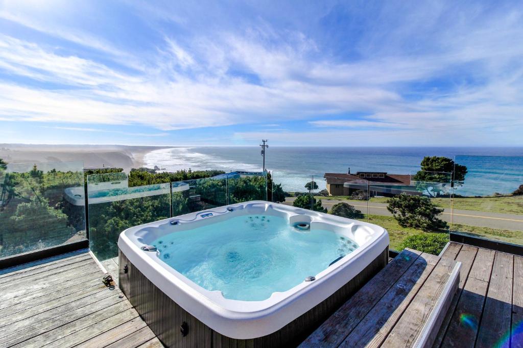 a hot tub on a deck with a view of the ocean at Friederichs' Beach House in Manchester