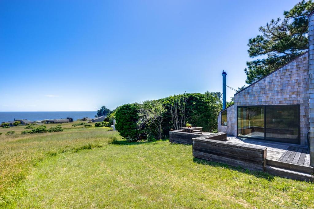 een huis op een veld met de oceaan op de achtergrond bij The Glass House in Sea Ranch