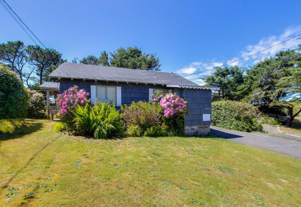 a small house with pink flowers in the yard at White Wing in Neskowin