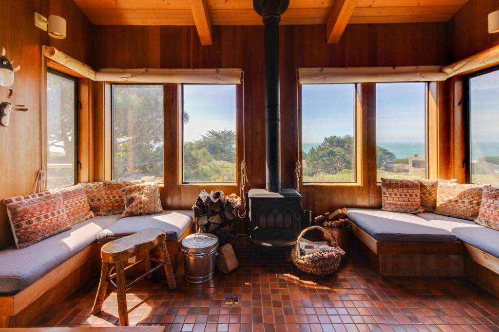 a living room with couches and a fireplace with windows at Gewing House in Sea Ranch
