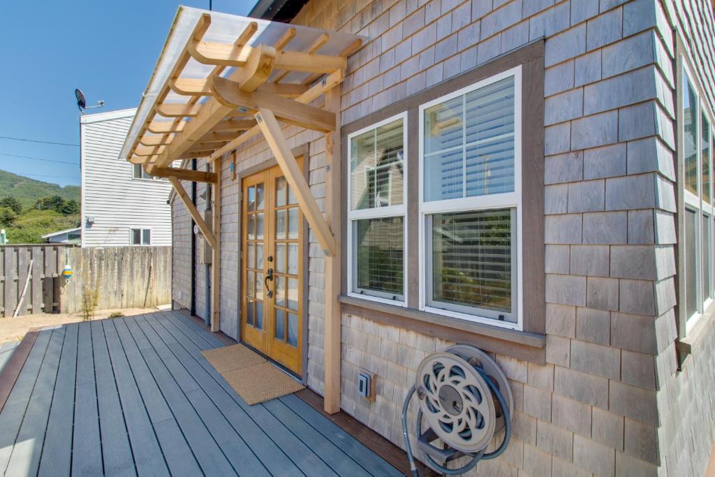 a house with a deck with a wooden door and windows at Rockaway Beach Bungalow in Rockaway Beach