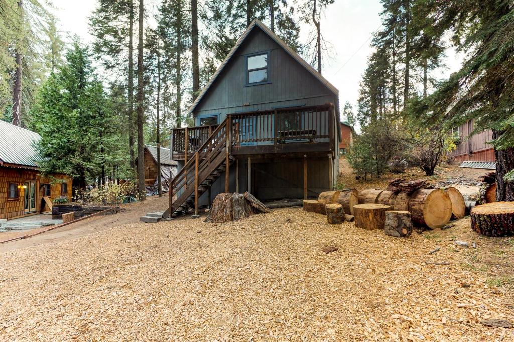 a cabin in the woods with a deck and logs at Pandora in Shaver Lake