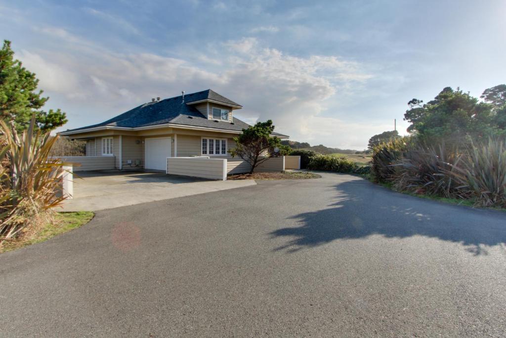 a white house with a blue roof on a driveway at Beach Hideaway in Bandon