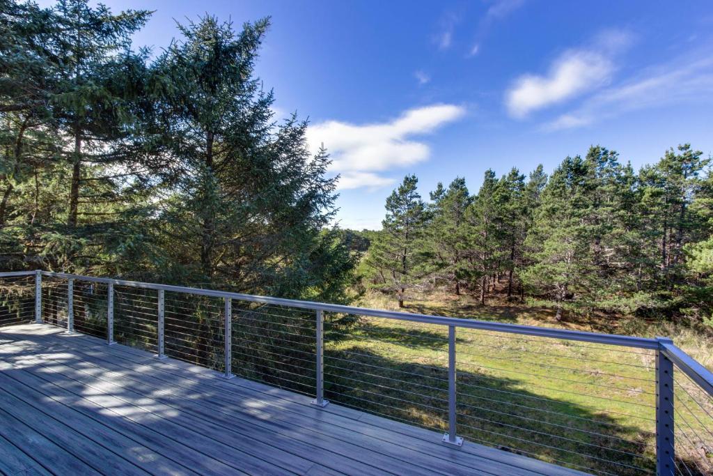 a wooden deck with a fence and trees at Rain or Shine in Neskowin