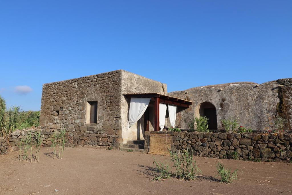 un antiguo edificio de piedra con una pared de piedra en Bent el Rhia dammusi en Pantelleria