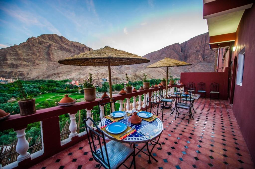 a balcony with tables and chairs with mountains in the background at Riad Sephora in Tinerhir