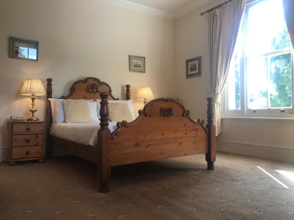 um quarto com uma cama de madeira e uma janela em Norfolk House em Maidenhead