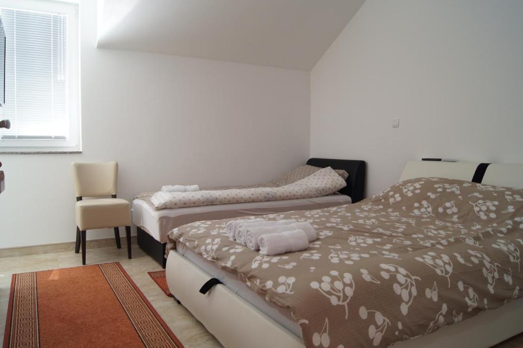 Guest room with two beds and a chair at exact SOBE ROOMS GAVRILO Booking listing. — SOBE ROOMS GAVRILO