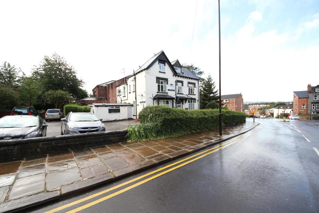 a rainy street with cars parked in a parking lot at Avalon Guest House in Leeds