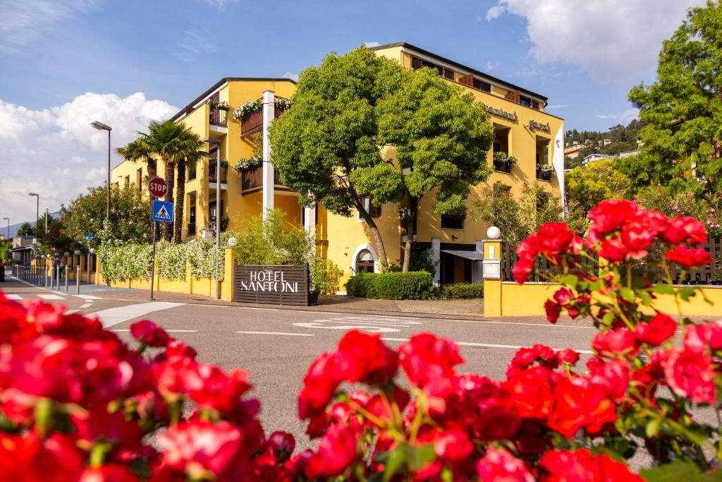Un mazzo di fiori rossi davanti a un edificio giallo di Hotel Santoni Freelosophy *** a Torbole