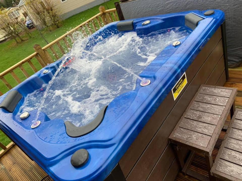 bañera de hidromasaje en una terraza con banco en Tranquil Lodge hot tub and free golf, en Swarland