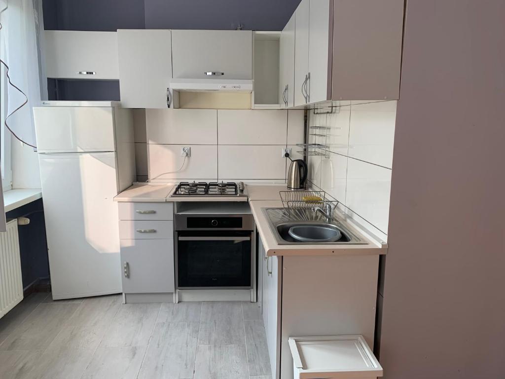 Elle comprend une petite cuisine avec des placards blancs et un évier. dans l'établissement Apartament Leśne, à Bydgoszcz