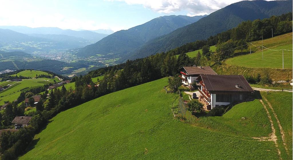 a house on a green hill with mountains in the background at Traterhof-Spinges in Mühlbach