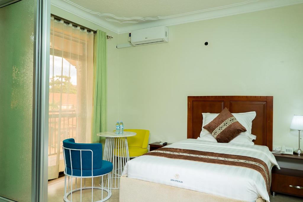 um quarto com uma cama, uma mesa e cadeiras em Jarin Hotel em Kampala