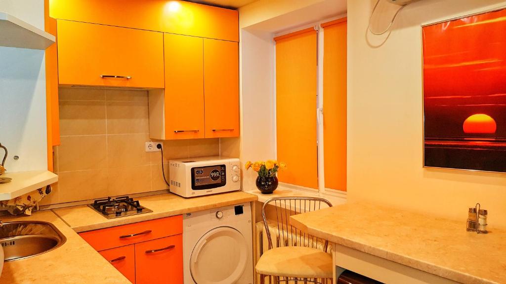 a kitchen with orange cabinets and a sink and a microwave at Apartment on Mirny Boulevard in the Very Center of the City in Kherson