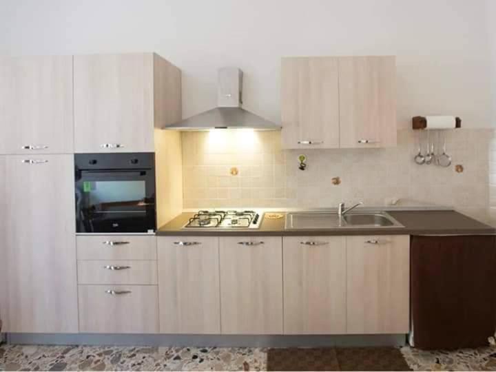 cocina con armarios blancos, fregadero y fogones en Vento di Scirocco, en Pozzallo