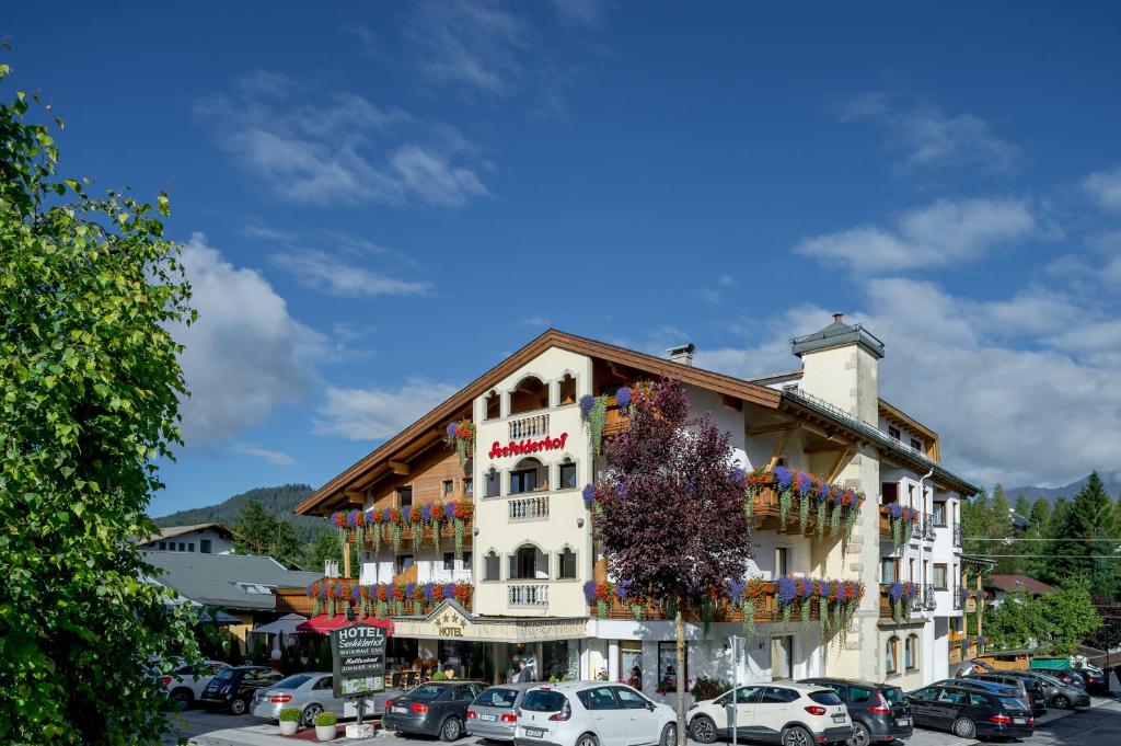 un grand bâtiment avec des voitures garées dans un parking dans l'établissement Hotel Seefelderhof, à Seefeld in Tirol