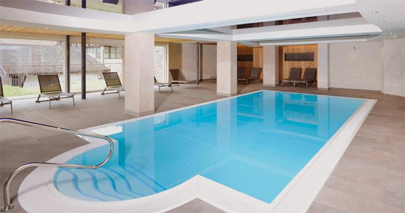 a large blue swimming pool in a building at Hotel Zum Löwen - Al Leone in Meltina