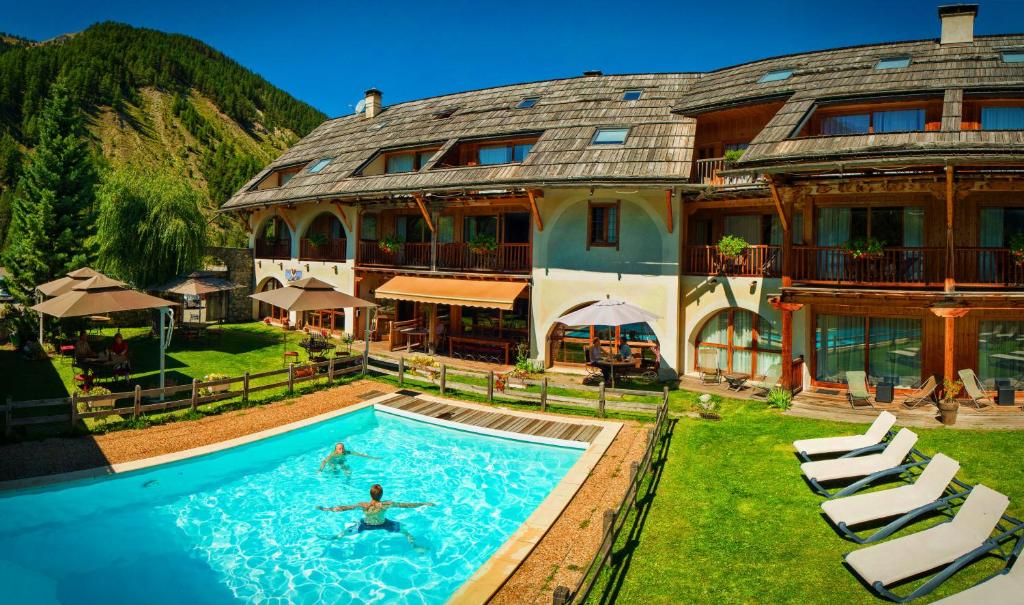une grande maison avec une piscine en face de celle-ci dans l'établissement Hôtel & Spa La Ferme de l'Izoard, à Arvieux