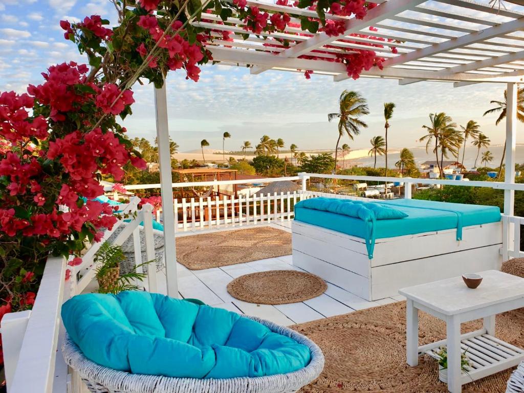 un patio con sillas azules, una mesa y flores en Pousada Duna Beach, en Jericoacoara