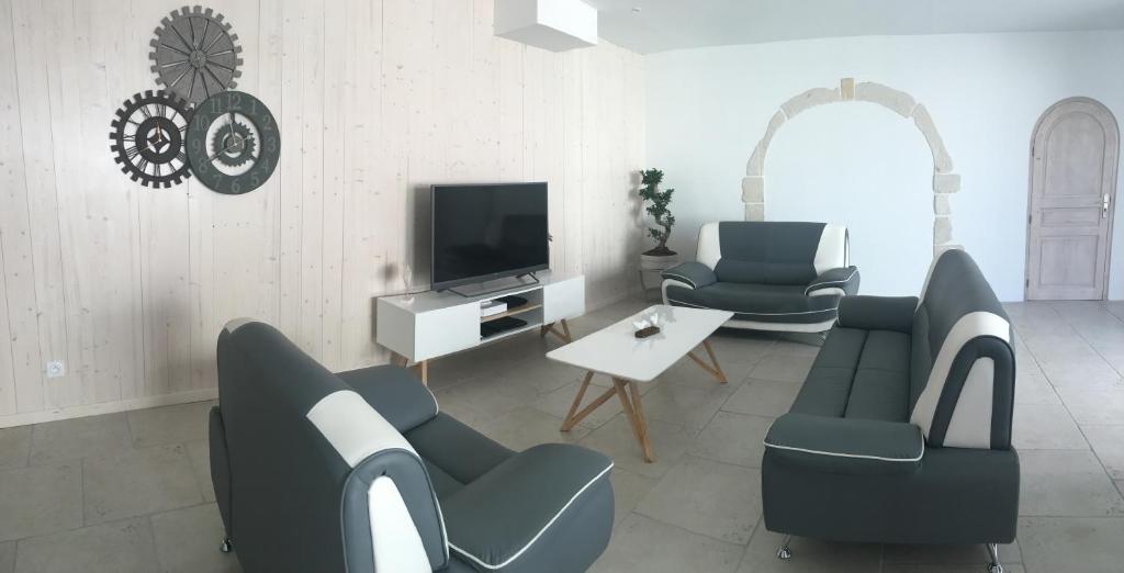 ein Wohnzimmer mit blauen Stühlen und einem TV in der Unterkunft Ma Ré Basse in La Flotte