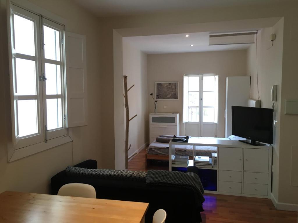 a living room with a couch and a desk with a television at Vidrio Apartment in Seville