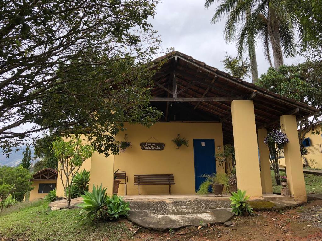 a yellow house with a blue door and a bench at Pousada Verde Maratea in Piranguçu