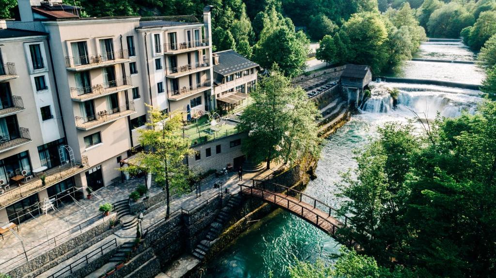 a bridge over a river with buildings and a waterfall at Hotel Kostelski Buk in Bihać