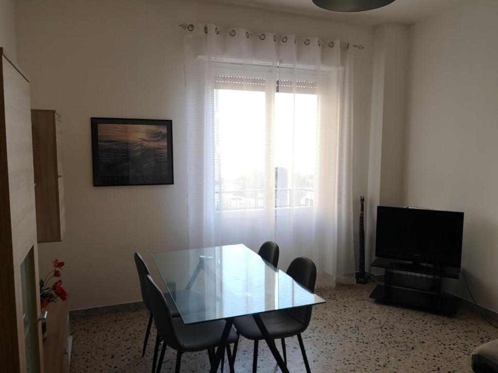 ein Esszimmer mit einem Glastisch und einem TV in der Unterkunft S'arrulloni in Cagliari