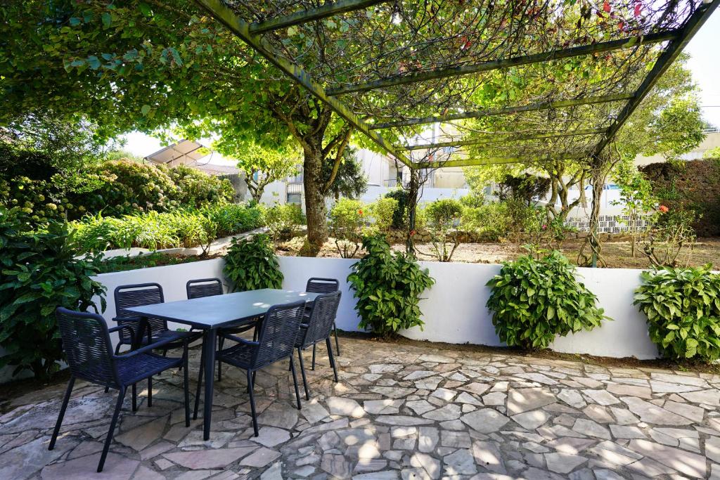 un patio con mesa y sillas bajo una pérgola en Comfy Sintra en Sintra