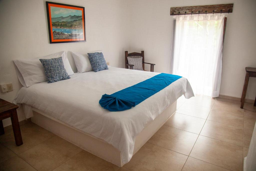 um quarto com uma grande cama branca com lençóis azuis em La Familia em San Blas