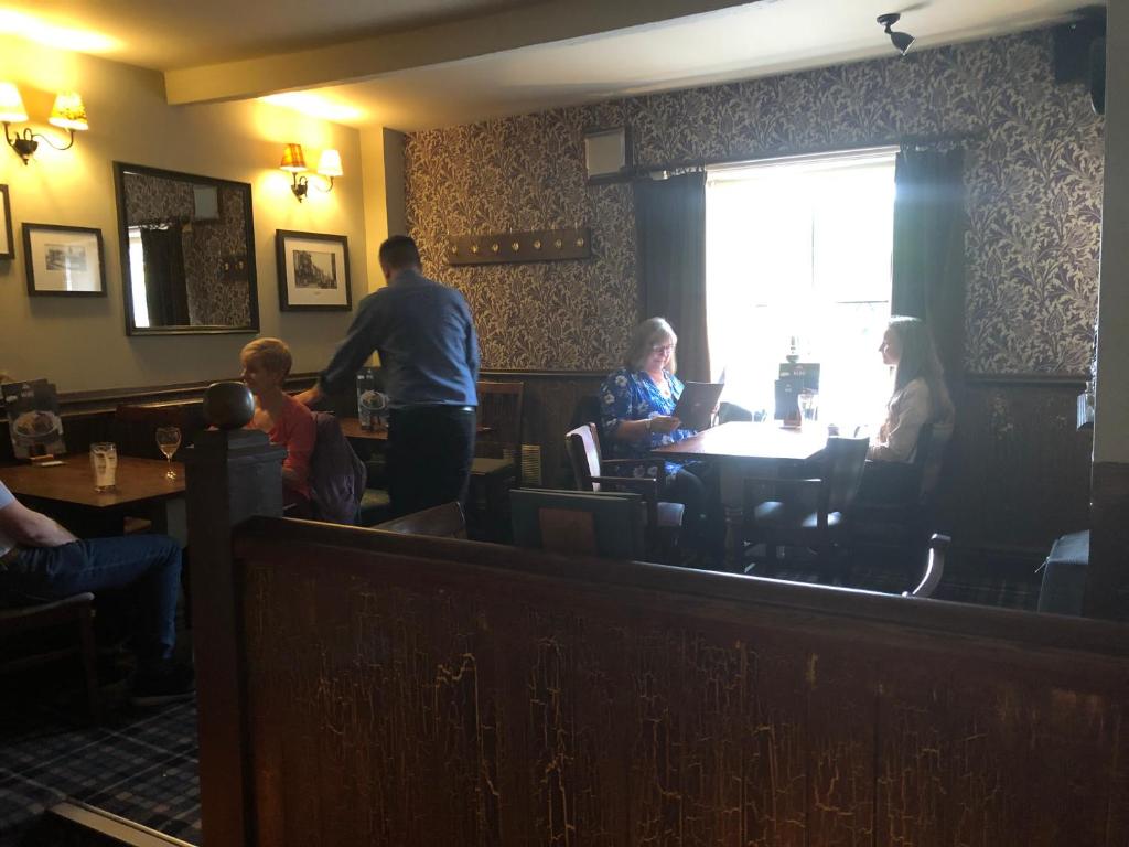 um grupo de pessoas sentadas em mesas em um restaurante em Black Dog Inn em Bolton