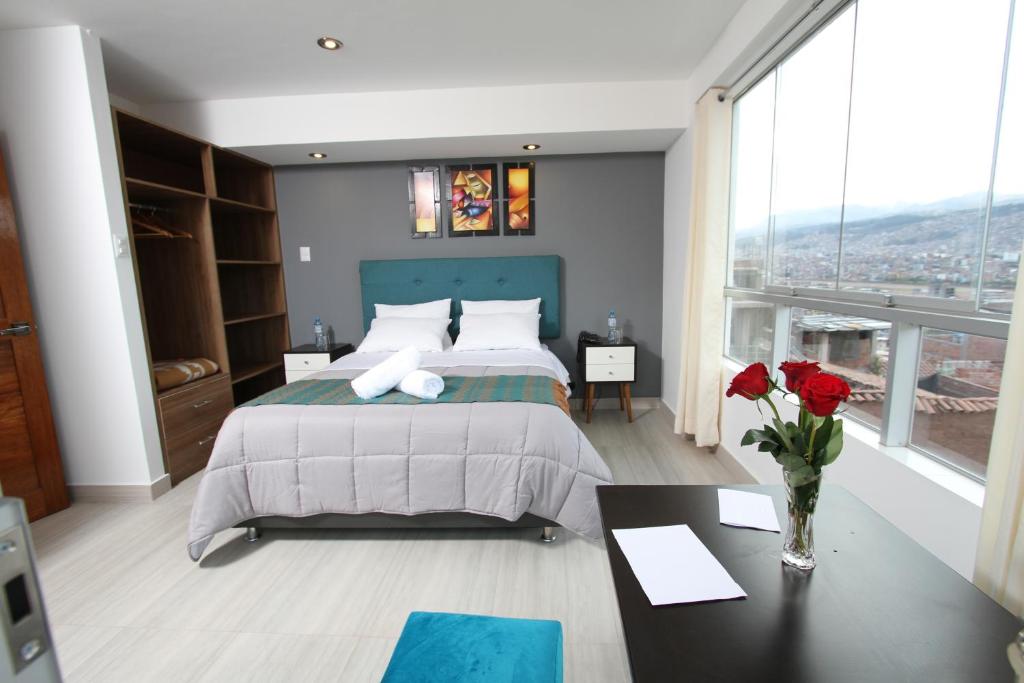 Un dormitorio con una cama grande y una mesa con rosas. en Latinos House Cusco en Cusco