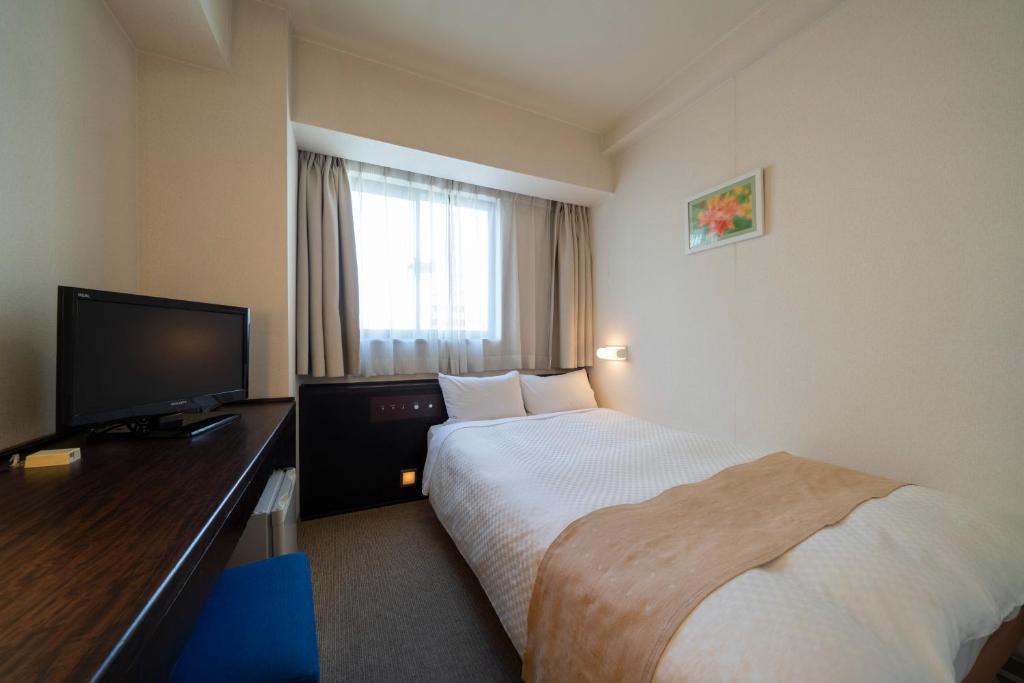 a hotel room with a bed and a flat screen tv at Hotel S-plus Nagoya Sakae in Nagoya