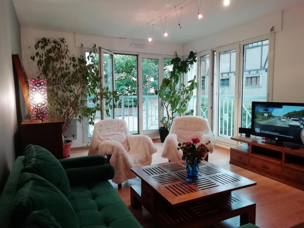 sala de estar con sillas blancas y TV en LE KATZALA en Mulhouse